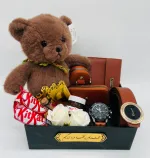 باکس هدیه ولنتاین مردانه کد V167 شامل عروسک خرسی وارداتی اورجینال، کیف پول جیبی چرم Gucci، جاریموتی چرم شیک، جاکارتی چرم زیپ دار، ساعت بند چرم طرح سه موتوره تقویم دار، کمربند ریلی با سگک وارداتی، شکلات خارجی کیت کت، نوتلا کوچک، گل رز معطر، تقویم طلایی و شیشه عشق در هاردباکس